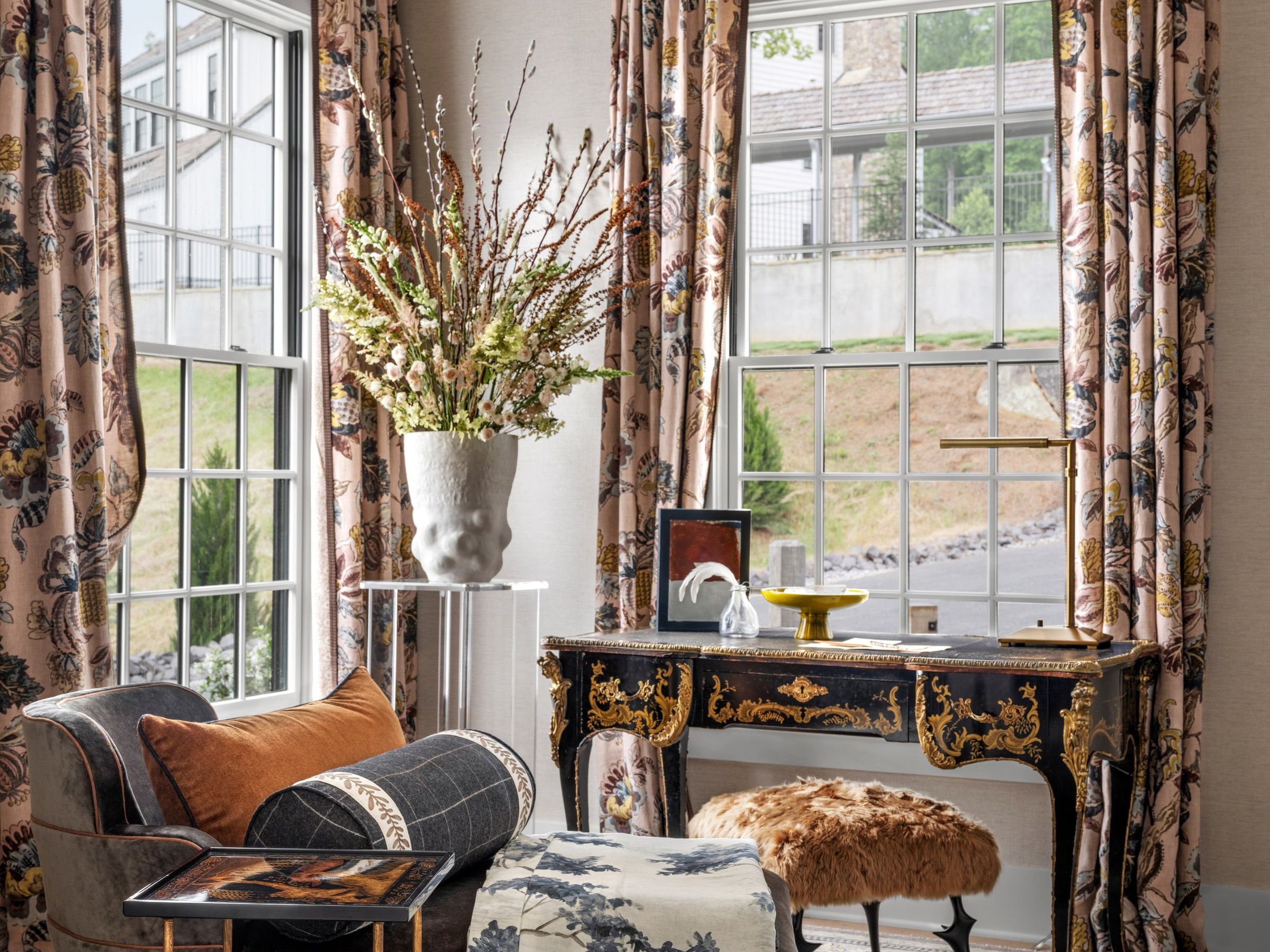 Home office with botanical drapery, a gilded antique desk, and a toile ottoman